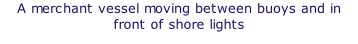 A merchant vessel moving between buoys and in front of shore lights