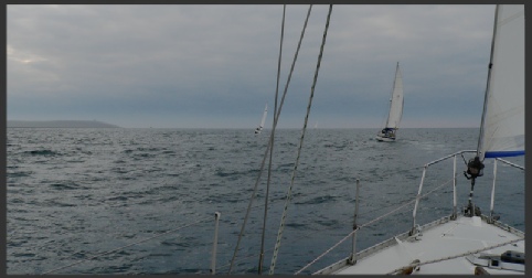 View ahead from a small boat showing other vessels and a headland
